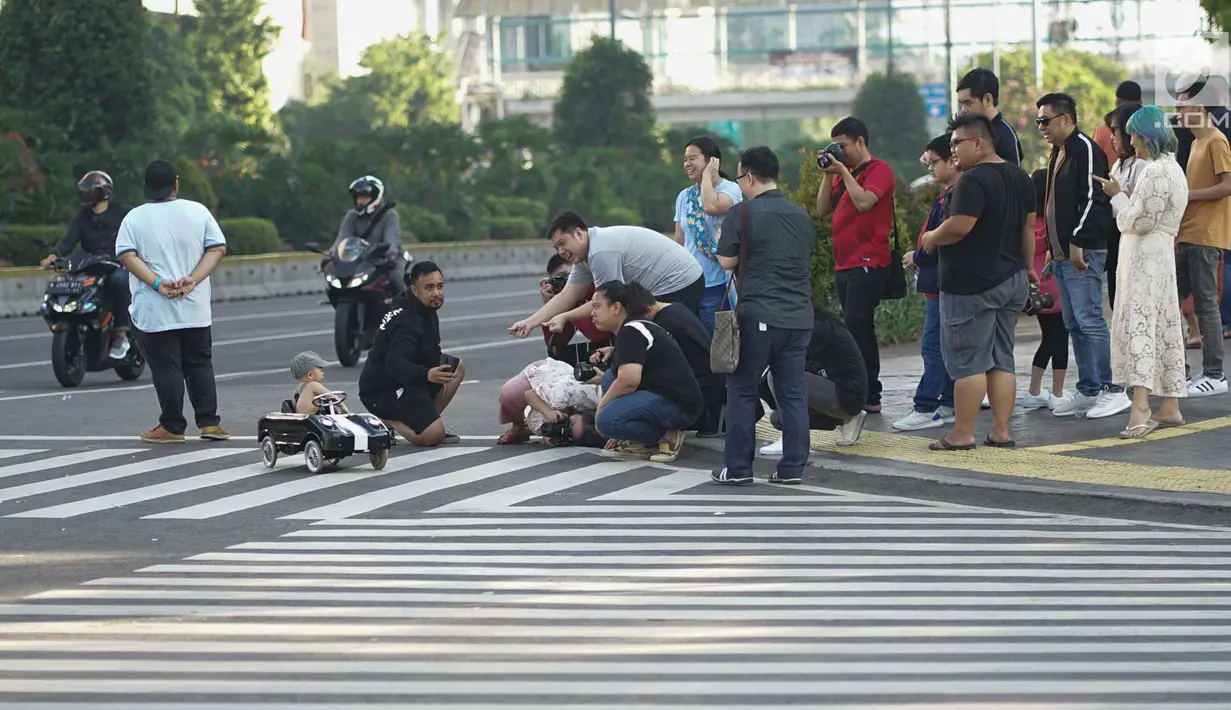 Seorang anak menjalani sesi pemotretan di Jalan MH Thamrin, Jakarta, Rabu (5/6/2019). Banyaknya warga Ibu Kota yang mudik ke kampung halaman untuk merayakan Hari Raya Idul Fitri membuat jalan protokol terpantau lengang. (Liputan6.com/Immanuel Antonius)