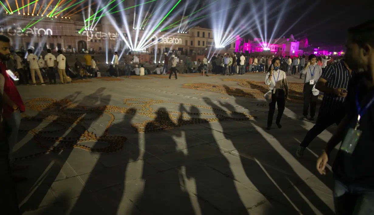 Bayangan orang-orang yang mengambil foto saat latihan pertunjukan laser jatuh di tepi sungai Saryu di Ayodhaya, India, Selasa (2/11/2021). Ratusan ribu lampu akan dinyalakan pada perayaan Deepotsav pada malam Diwali. (AP Photo/Rajesh Kumar Singh)
