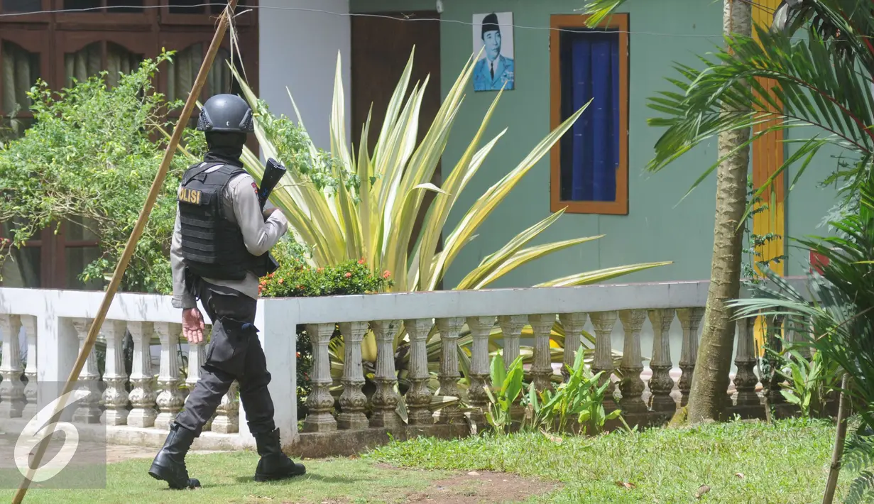 Petugas Kepolisian Brimob berjaga disekitar area rumah terduga teroris di Setu, Tangerang Selatan, Rabu (21/12). Setelah AN diinterogasi tim mendapatkan informasi bahwa bom akan diledakkan pada akhir tahun. (Liputan6.com/Helmi Affandi)