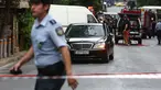 Seorang polisi berjalan dekat sebuah mobil di lokasi ledakan di pusat kota Athena, Kamis (25/5). Mantan PM Yunani, Lucas Papademos mengalami luka bakar di kaki dan tangannya akibat sebuah paket meledak di dalam mobil tersebut. (AP Photo/Yorgos Karahalis)