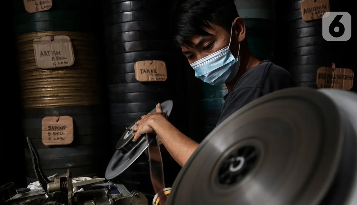 Adul (29) menyiapkan film seluloid 35mm untuk pertunjukan layar tancap di gudang rumahnya di Jakarta, Rabu (28/4/2021). Biasanya Adul dan ayahnya menyewakan peralatan dan film seluloid 35mm untuk layar tancap dengan harga Rp50 ribu sampai Rp200 ribu saja. (Liputan6.com/Johan Tallo)