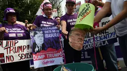 Aktivis membuang foto Presiden terpilih AS, Donald Trump ke dalam tong sampah di depan kedutaan AS, Manila, Filipina (20/1). Dunia akan menyaksikan pelantikan Donald Trump dan Mike Pence sebagai Presiden dan Wakil Presiden AS. (AFP Photo/Ted Aljibe)