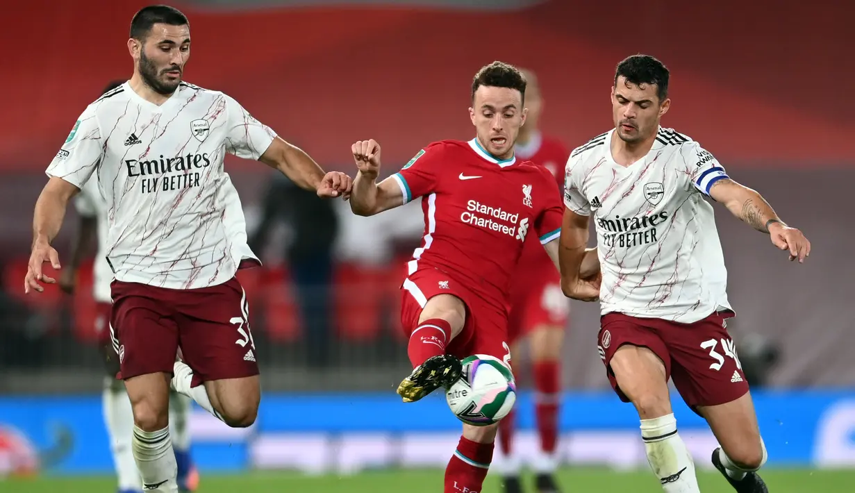 Gelandang Arsenal, Granit Xhaka, berebut bola dengan penyerang Liverpool, Diogo Jota, pada laga Piala Liga Inggris di Stadion Anfield, Jumat (2/10/2020) dini hari WIB. Arsenal menang 5-4 atas Liverpool lewat adu penalti. (AFP/Laurence Griffiths)