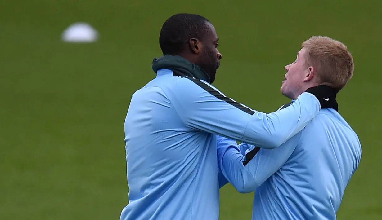 Pemain Manchester City, Yaya Toure bercanda dengan Kevin De Bruyne saat sesi latihan jelang laga Liga Champions di Manchester, Selasa (6/3/2018). Manchester City akan berhadapan dengan FC Basel. (AFP/ Oli Scarff)