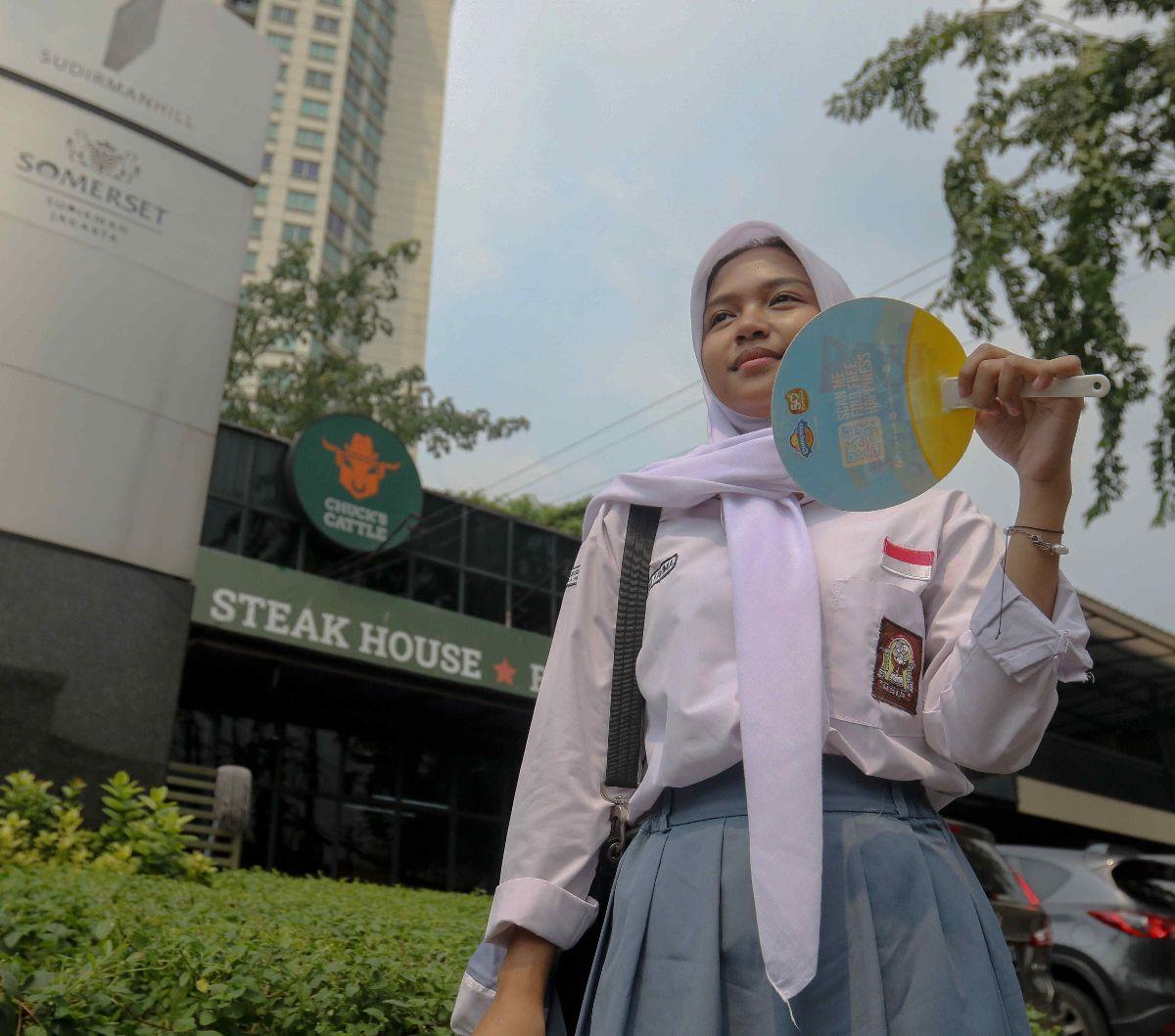Pelajar menggunakan kipas saat menunggu tranportasi umum di kawasan Bendungan Hilir, Jakarta, Rabu (8/5/2024). Dalam beberapa hari terakhir suaca panas melanda sejumlah wilayah di Indonesia, termasuk Jakarta. Foto: Liputan6.com/Herman Zakharia<br>