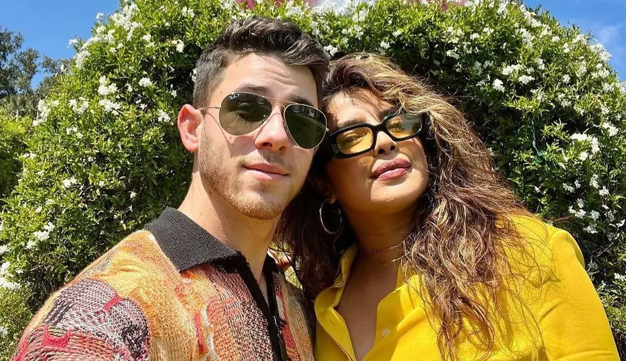 <p>Pasangan Nick Jonas dan Priyanka Chopra merayakan Paskah dengan outfit bernuansa kuning. Priyanka memilih kemeja kuning polos, sedangkan Nick Jonas mengenakan sweater rajut berkerah dengan motif abstrak. Keduanya berpose selfie di depan dekorasi taman berbentuk telinga kelinci yang gemas. Foto: Instagram.</p>