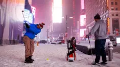 Dua pria bermain golf dengan bola tenis saat badai salju melanda kawasan Times Square, New York, (14/3). NWS menetapkan status darurat untuk negara bagian New York dan New Jersey yang terancam dilanda badai salju. (AP/Mark Lennihan)
