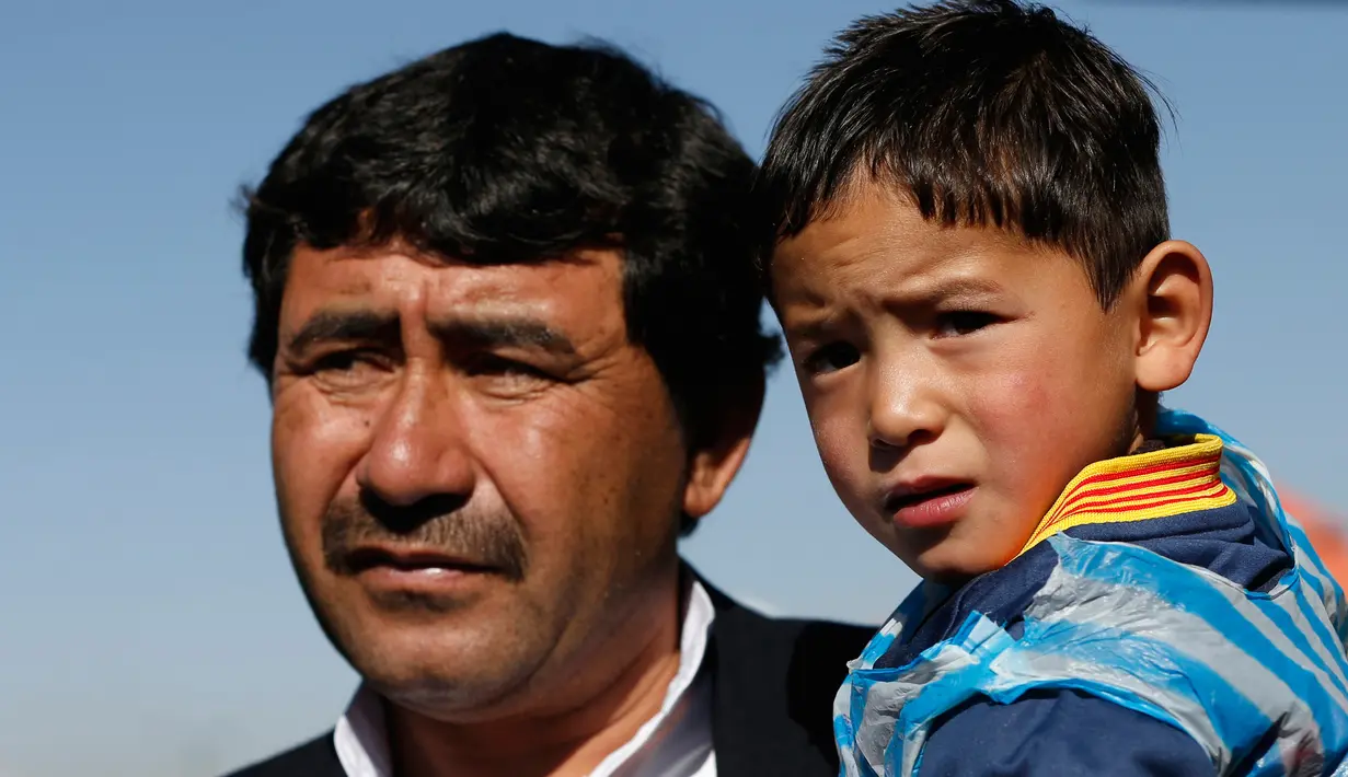 Murtaza Ahmadi digendong oleh ayahnya saat berada di markas Federasi Sepak Bola Afghanistan di Kabul, (2/2). Ahmadi  merupakan penggemar berat dari pemain internasional Argentina tersebut. (REUTERS / Omar Sobhani)