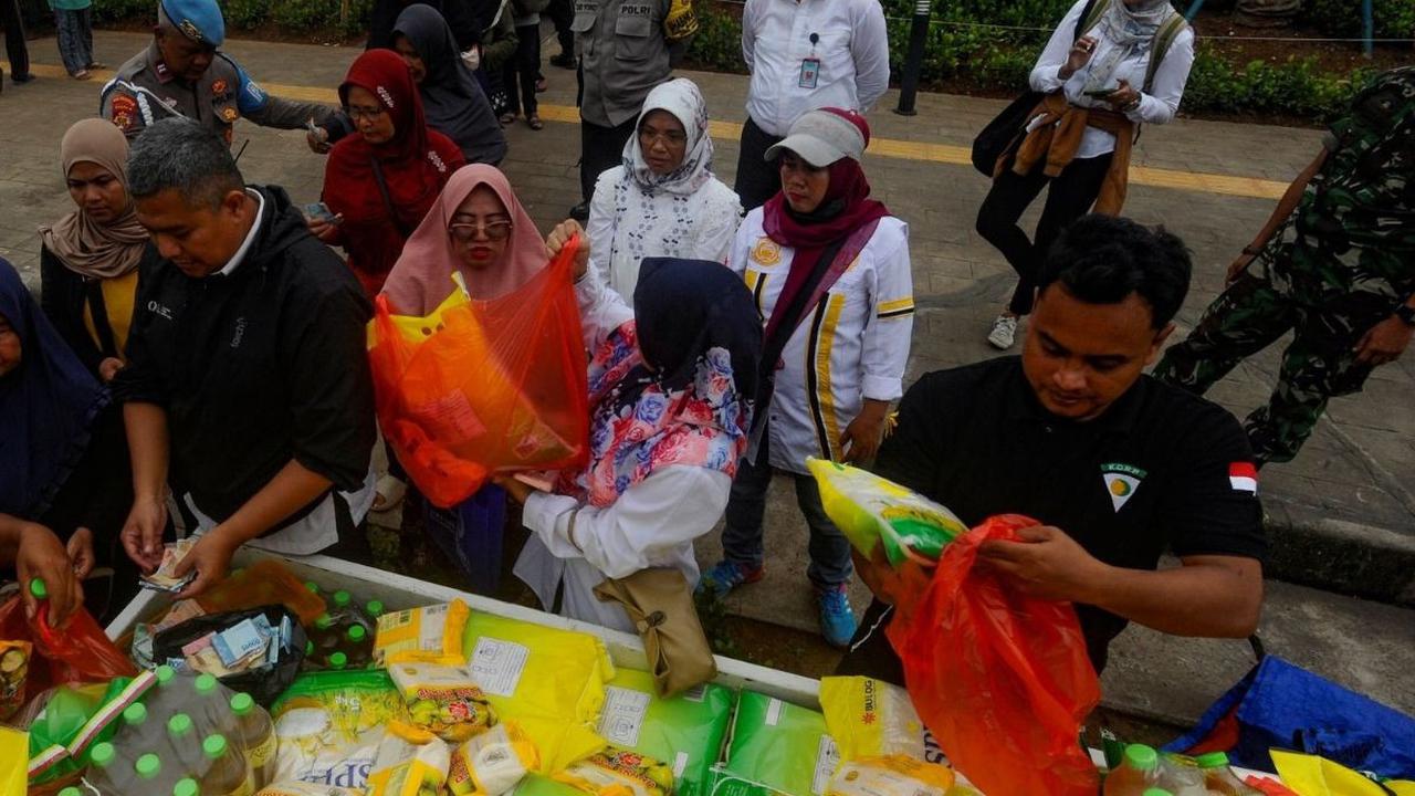Petugas saat melayani warga yang antre saat memberi beras dan sembako murah di kegiatan Pasar Murah di halaman kantor Kecamatan Pamulang, Tangsel. Foto: merdeka.com / Arie Basuki