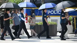 Petugas polisi menggunakan payung untuk melindungi diri dari terik matahari di sebuah jalan di Seoul, Korea Selatan, Senin, 3 Agustus 2026. (AFP/ Jung Yeon-je)