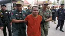 Yem Chrin (tengah) dikawal oleh petugas polisi saat tiba di Pengadilan Provinsi Battambang,Kamboja,Kamis (3/12). Pengadilan Kamboja menghukum Yem Chrin  25 tahun penjara dengan kasus pembunuhan dan penyebaran HIV lebih dari 270 orang. (REUTERS/Stringer)
