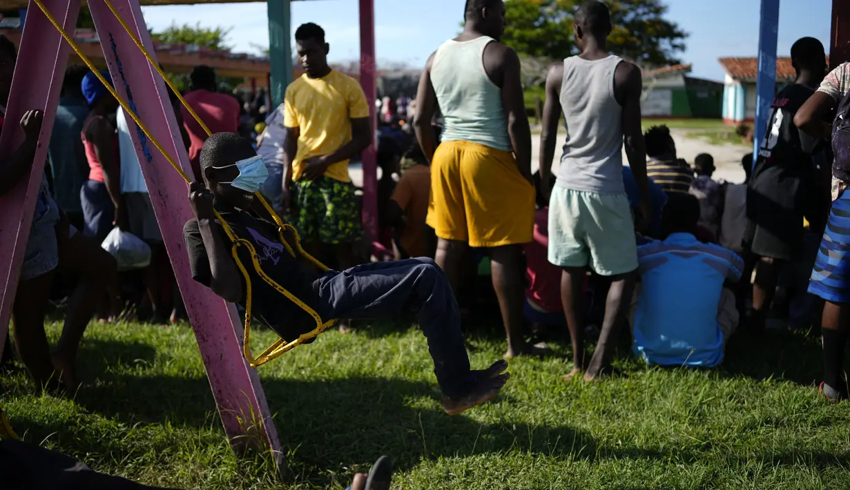 Seorang imigran Haiti mengenakan masker pelindung menutupi mata berayun di sebuah perkemahan wisata di Sierra Morena, di provinsi Villa Clara, Kuba (25/5/2022). (AP Photo/Ramon Espinosa)