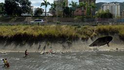 Pria mencari logam berharga di saluran pembuangan limbah di Sungai Guaire, di Caracas, (1/2). Menemukan emas hal yang diharapkan para warga, namun kawat tembaga sudah cukup untuk menahan kelaparan. (AFP Photo/Federico Parra)