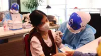 Petugas medis dengan mengenakan topeng superhero menyuntikkan vaksin Sinonvac kepada anak-anak saat mengikuti vaksinasi kedua di Gedung  Otoritas Jasa Keuangan (OJK), Jakarta, Minggu (16/01/2022). (Liputan6.com/Angga Yuniar)