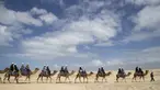 Wisatawan menikmati perjalanan manaiki unta dipandu pawangnya di sepanjang bukit pasir di Stockton Beach, Australia, Jumat (6/11/2020). Stockton Beach adalah rumah bagi bukit pasir bergerak terbesar di Belahan Bumi Selatan dengan beberapa di antaranya Tinggi 30 meter (98 kaki). (AP Photo/Mark Baker)