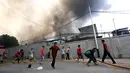 Warga mencoba memadamkan api yang membakar pemukiman padat penduduk di kawasan Manggarai, Jakarta, Rabu (10/7/2019). Sebanyak 27 Unit mobil pemadam kebakaran diterjunkan untuk memadamkan api yang melanda pemukiman di dekat Stasiun Manggarai tersebut. (Kapanlagi.com/Budy Santoso)