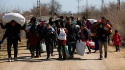 Para migran yang membawa barang-barang berjalan dekat perbatasan Turki dengan Yunani di Gerbang Pazarkule, Edirne, Turki, Selasa (3/3/2020). Turki membuka perbatasannya dengan Yunani setelah eskalasi militer antara pasukan Turki dan Suriah memuncak di barat laut Suriah. (AP Photo/Darko Bandic)