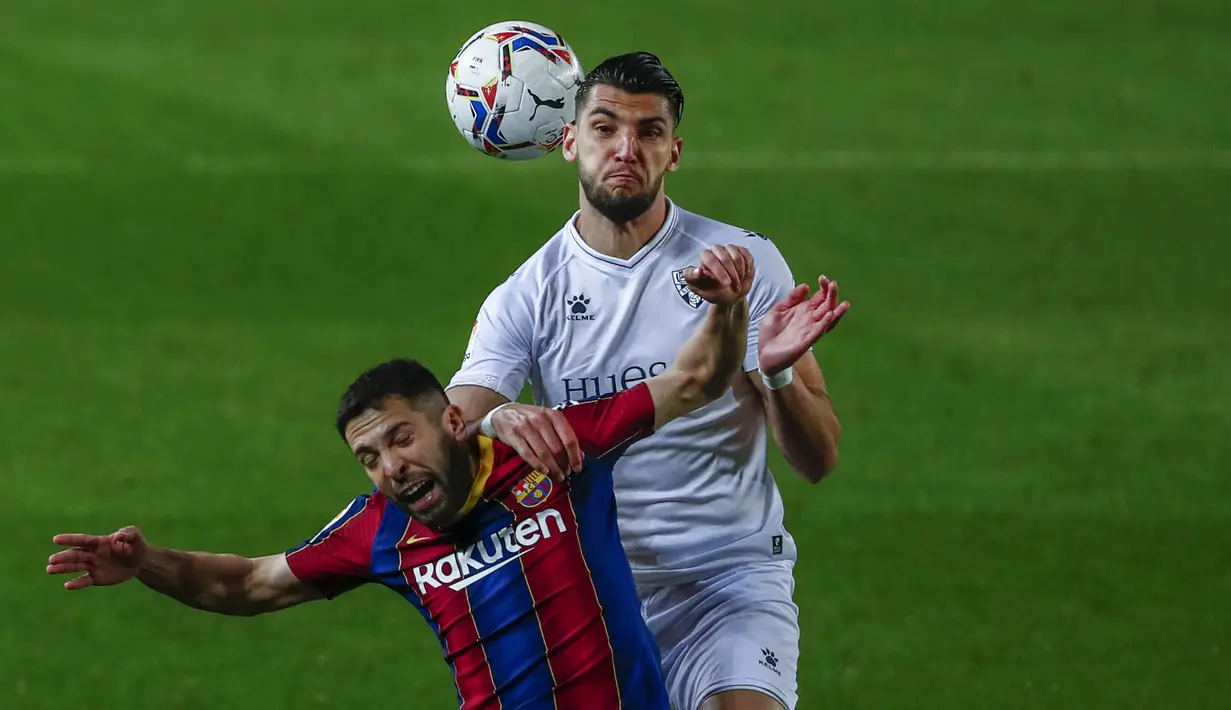 Bek Barcelona, Jordi Alba (kiri) berduel udara dengan striker SD Huesca, Rafa Mir dalam laga lanjutan Liga Spanyol 2020/2021 pekan ke-27 di Camp Nou Stadium, Barcelona, Senin (15/3/2021). Barcelona menang 4-1 atas SD Huesca. (AP/Joan Monfort)