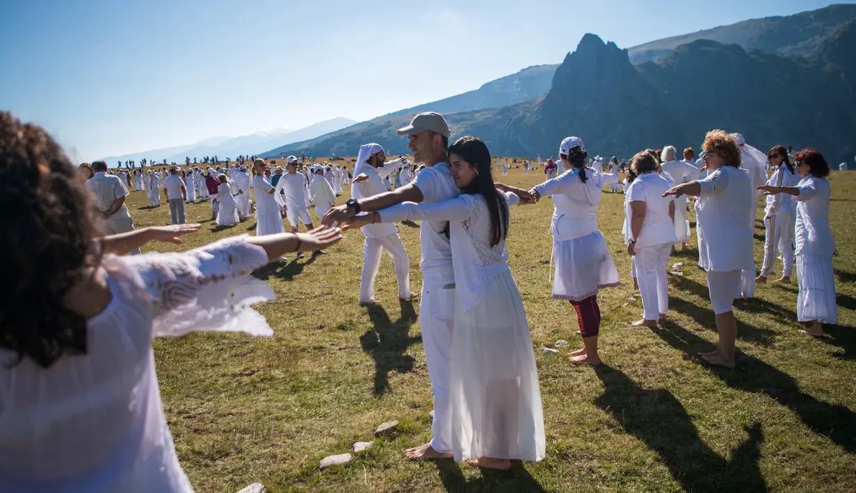 Anggota gerakan keagamaan internasional White Brotherhood menari di puncak Gunung Rila, Bulgaria, Senin (19/8/2019). Para peserta menari selama lebih dari satu jam di bawah suara nyanyian dan biola. (NIKOLAY DOYCHINOV/AFP)