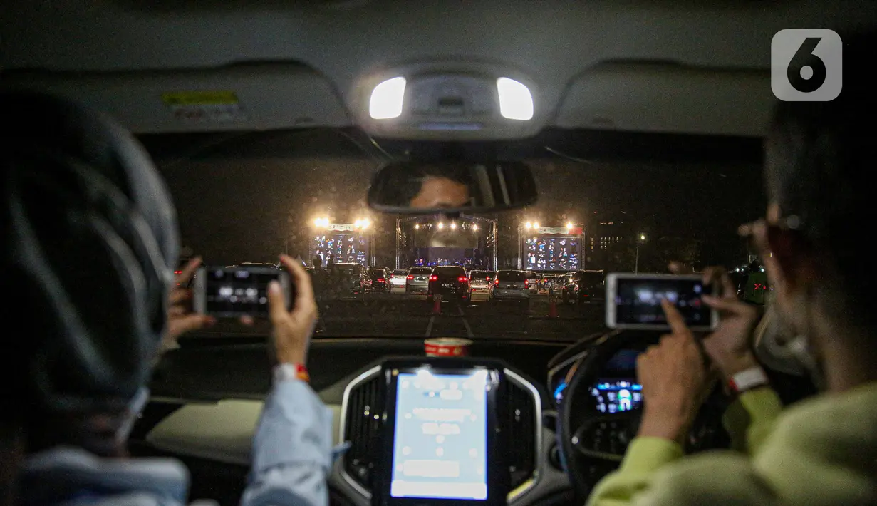 Penonton mengambil gambar konser New Live Experience 2020 pada hari kedua di Parkir Barat JIExpo Kemayoran, Jakarta, Minggu (30/8/2020). Konser musik dengan konsep drive-in tersebut digelar dengan menerapkan protokol kesehatan untuk mencegah penyebaran COVID-19. (Liputan6.com/Faizal Fanani)