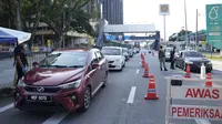 Polisi memeriksa penumpang di kendaraan pada hari pertama Perintah Kontrol Gerakan Penuh (MCO) di Kuala Lumpur, Malaysia (1/6/2021). Penguncian kedua dilakukan untuk mengatasi pandemi yang memburuk yang telah menempatkan sistem perawatan kesehatannya di ambang kehancuran. (AP Photo/Vincent Thian)