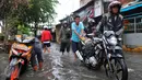 Warga melawati jalanan yang banjir di kawasan Jakarta Barat, Jumat (26/2). Ketinggian banjir mencapai 50-60cm.  (Liputan6.com/Faisal R Syam)