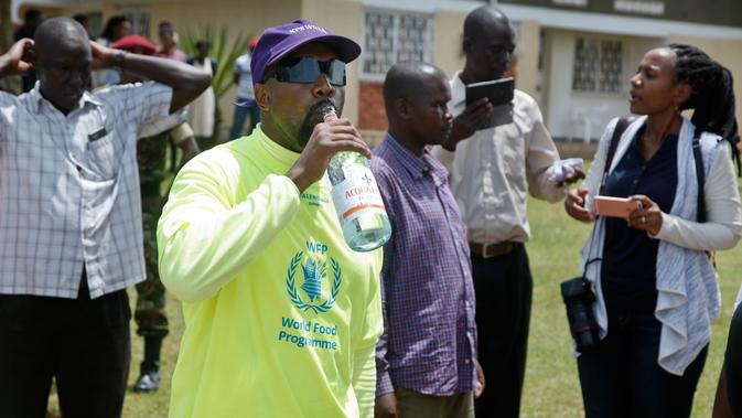 Rapper AS, Kanye West minum air disela kunjungannya ke Kampung Anak UWESCO di Masulita, Uganda, Selasa (16/10). Ketika di sana, Kanye West membagikan ratusan pasang sepatu Yeezy Boost 350 V2s kepada anak-anak yatim piatu. (AP/Stephen Wandera)