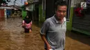 Warga melintasi banjir yang melanda kawasan bantaran kali Cisadane, Tangerang, Jumat (26/4). Banjir kiriman setinggi 2 meter sempat melanda kawasan akibat curah hujan yang tinggi di bogor membuat derasnya air mengalir jauh sampai ke tempat ini. (Liputan6.com/Johan Tallo)