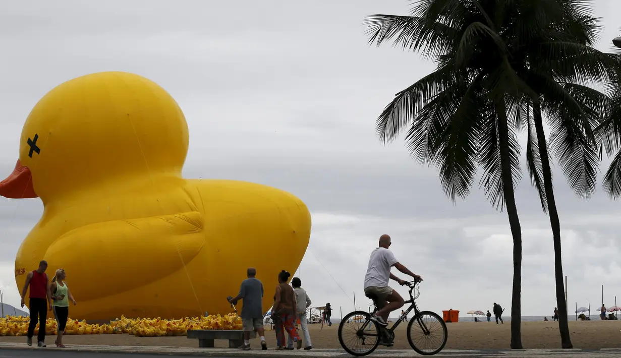 Warga beraktivitas di sekitar balon raksasa berbentuk bebek di pantai Copacabana, Brasil, Minggu (25/10). Kampanye "I will not pay the Duck" ini mengacu pada industri yang membayar pajak tinggi. (REUTERS/Sergio Moraes)