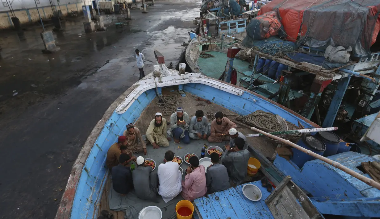 Nelayan berbuka puasa selama bulan suci Ramadhan, di galangan kapal, di Karachi, Pakistan, Selasa (20/4/2021). (AP Photo / Fareed Khan)