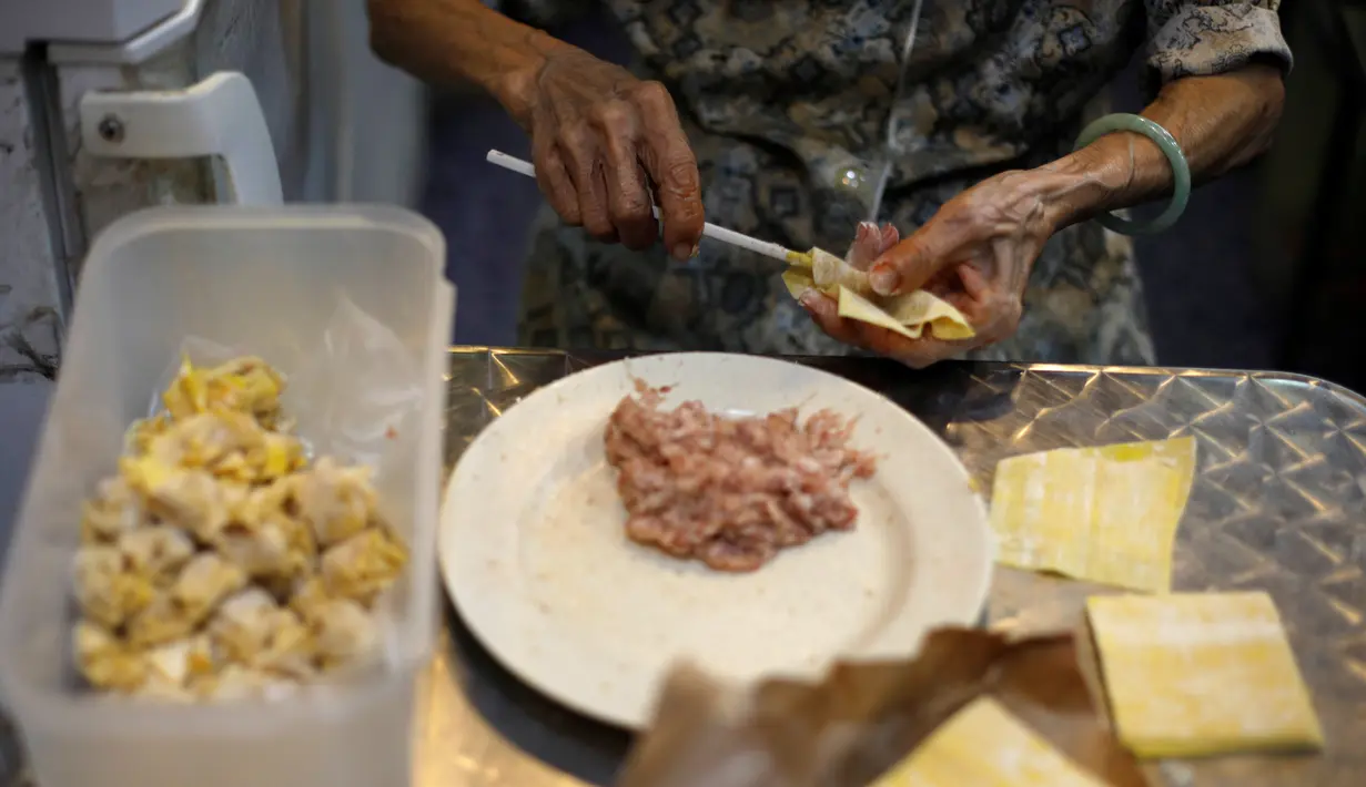 Nenek Leong Yuet Meng, pemilik usaha Nam Seng Noodle House membungkus isian daging ke dalam pangsit di warungnya di Singapura (22/3). Nenek Leong disebut sebagai salah satu pedagang makanan tertua di Asia dan bahkan mungkin dunia. (Reuters/Edgar Su)