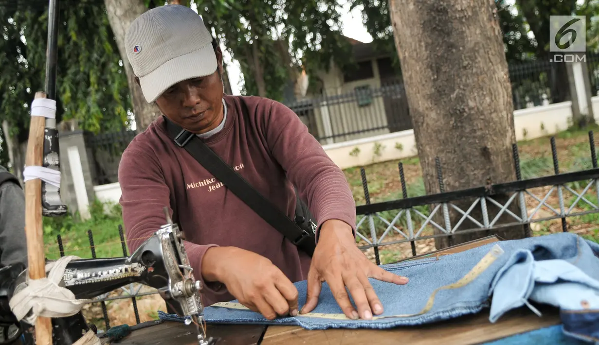 Penjahit keliling mengukur pakaian pelanggan yang akan dijahit ulang, Jakarta, Kamis (22/6). Jelang lebaran, penjahit keliling mulai banyak menerima orderan warga untuk sekedar memotong atau mengecilkan pakaian. (Liputan6.com/Yoppy Renato)