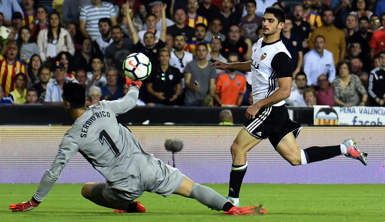 Kiper Sevilla, Sergio Rico Gonzalez, berusaha memblok bola sepakan gelandang Valencia, Manuel Guedes, pada laga La Liga Spanyol di Stadion Mestalla, Sabtu (21/10/2017). Valencia menang 4-0 atas Sevilla. (AFP/Jose Jordan)