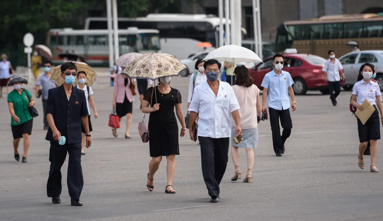 Pejalan kaki melewati alun-alun saat suhu tinggi mencapai 34 derajat celsius di Pyonyang, Korea Utara, Rabu (21/7/2021). Musim Panas dimulai pada bulan Juni hingga Agustus, dan puncak musim panas adalah bulan Agustus. (KIM Won Jin / AFP)