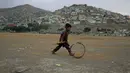 Seorang bocah Afghanistan mendorong roda saat terjadi badai pasir di pinggiran Kabul, Afghanistan (25/8/2020). Sebuah badai pasir hebat melanda Kabul. Badai menyebabkan jarak pandang jadi berkurang. (AP Photo / Rahmat Gul)