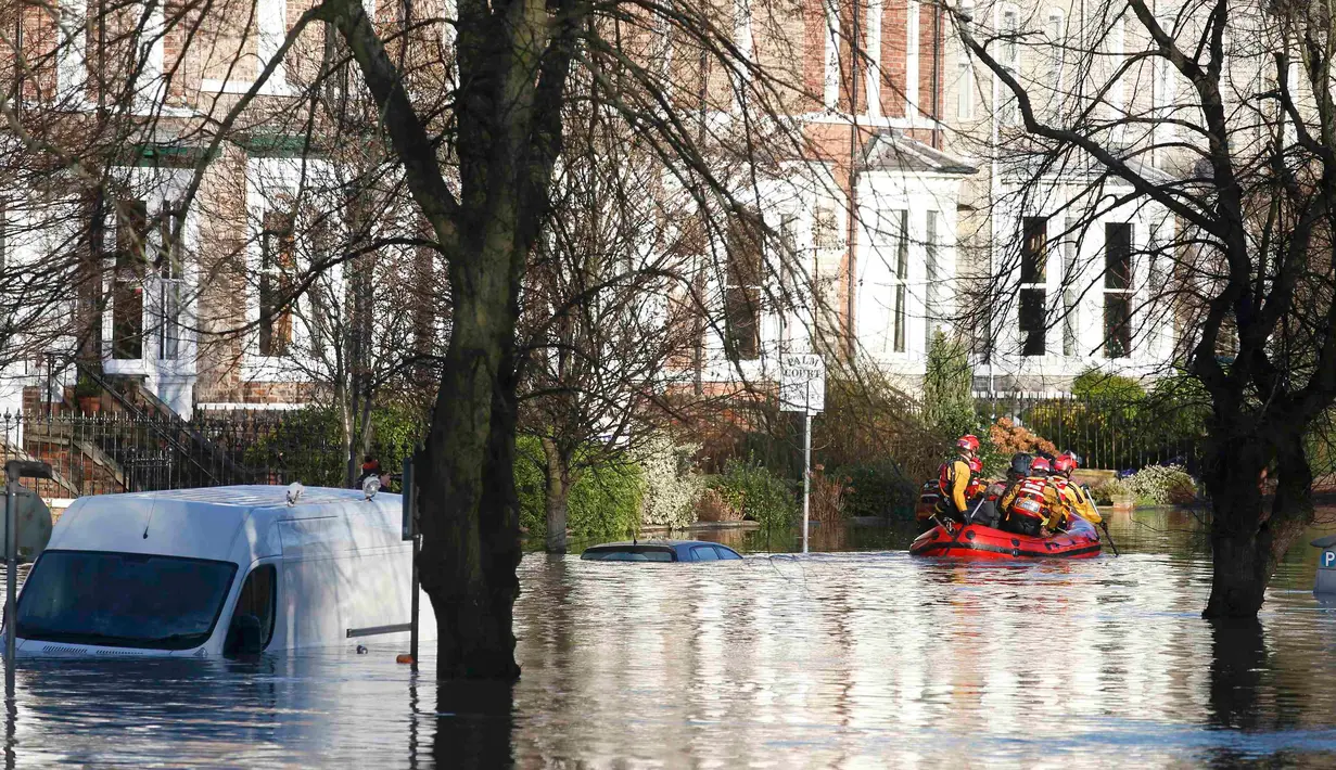 Tim regu penyelamat menyisir lokasi pemukiman warga yang terendam banjir menggunakan perahu karet di York, Inggris utara, Minggu (27/12). Banjir akibat luapan sungai Ouse yang telah memperburuk sejumlah wilayah Inggris utara. (REUTERS/Phil Noble)