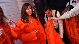 Pengunjung diberikan baju tahanan saat tiba di bar koktail Alcotraz, London , 11 Oktober 2018. Bar berkonsep penjara ini terinspirasi dari karya fiksi terkenal, Shawshank Redemption dan serial Netflix bertajuk 'Orange Is a New Black'. (BEN STANSALL / AFP)