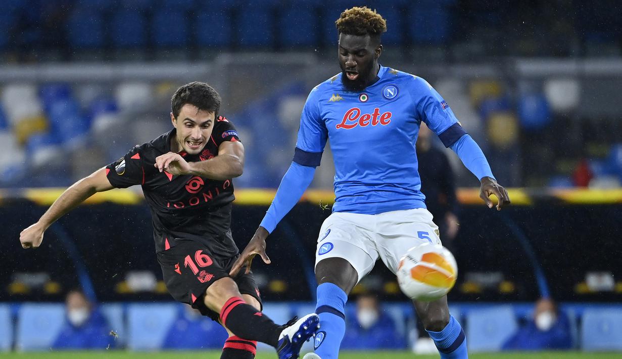 Gelandang Real Sociedad, Ander Guevara (kiri), melepaskan tendangan dibawah tekanan gelandang Napoli, Tiemoue Bakayoko, dalam laga lanjutan Liga Europa 2020/21 Grup F di Diego Armando Maradona Stadium, Kamis (10/12/2020). Real Sociedad bermain imbang 1-1 dengan Napoli. (AFP/Alberto Pizzoli)