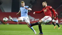 Pemain Manchester City Kevin De Bruyne (kiri) mencoba menghalau tendangan pemain Manchester United Luke Shaw pada pertandingan semifinal Piala Liga Inggris di Old Trafford, Manchester, Inggris, Rabu (6/1/2021). Manchester City mengalahkan Manchester United 2-0. (Peter Powell/Pool via AP)