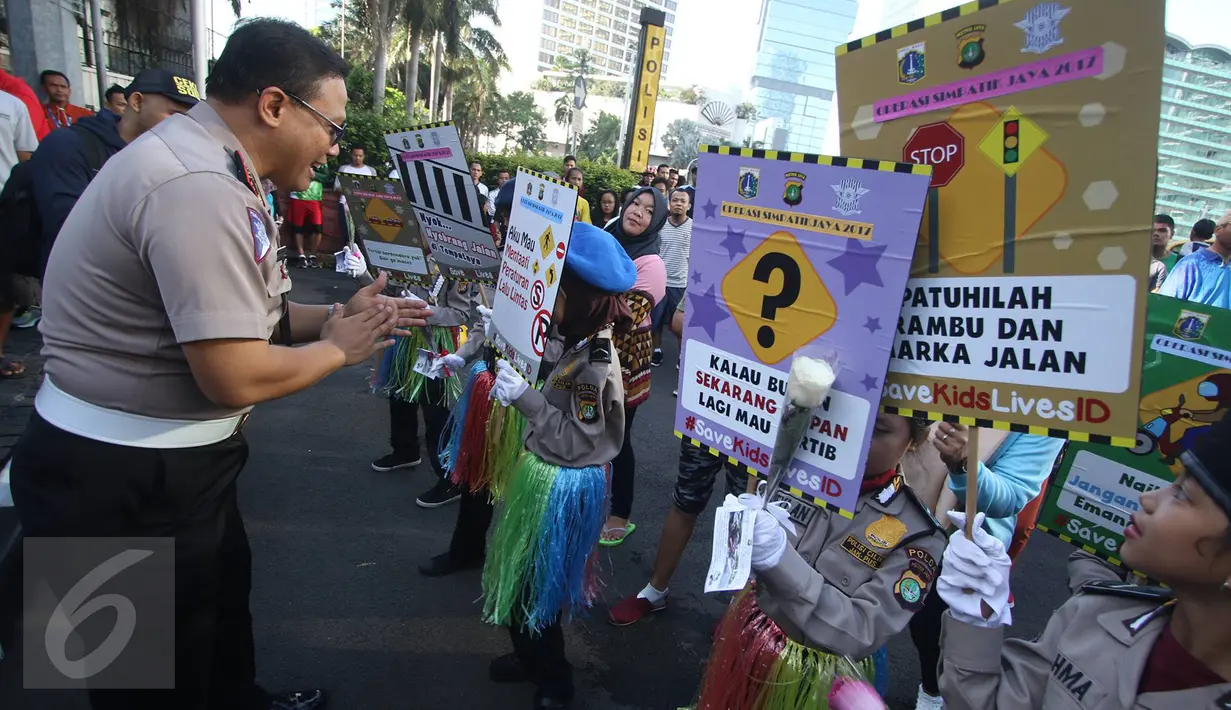 Polisi ikut berpartisipasi bersama polisi cilik saat melakukan kampanye keselamatan berkendara di kawasan Bundaran HI, Jakarta, Minggu (12/3). (Liputan6.com/Immanuel Antonius)
