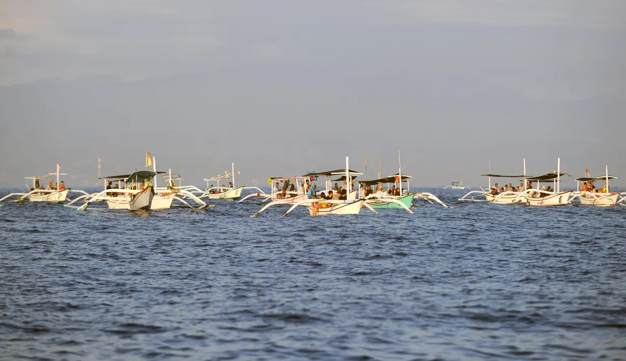 Wisatawan di atas perahu selama tamasya menyaksikan lumba-lumba di perairan Pantai Lovina di Singaraja, Bali, Jumat (30/10/2020). Pantai Lovina merupakan salah satu destinasi pariwisata di Bali yang sering dikunjungi untuk menikmati matahari terbit dan lumba-lumba di laut lepas (SONNY TUMBELAKA/AFP)