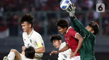 Pemain belakang Timnas Indonesia U-19, Ahmad Rusadi (kedua kanan) berebut bola atas dengan penjaga gawang Thailand U-19, Narongsak Naengwongsa pada lanjutan penyisihan grup A Piala AFF U-19 2022 di Stadion Patriot Candrabhaga, Bekasi, Jawa Barat, Rabu (6/7/2022). Laga kedua tim berlangsung imbang 0-0. (Liputan6.com/Helmi Fithriansyah)