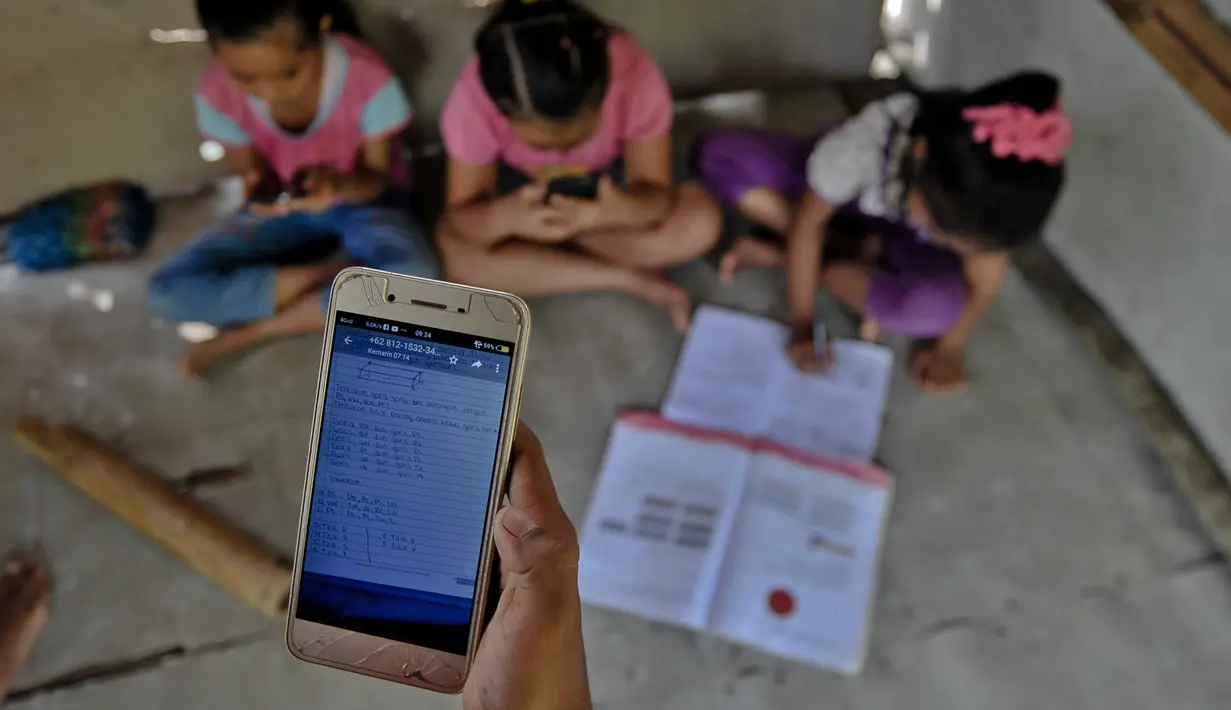 Siswa sekolah dasar mengikuti pembelajaran secara online menggunakan smartphone mereka di sebuah gubuk di bukit Temulawak, Yogyakarta, Jumat (8/5/2020). Mereka harus ke atas bukit untuk mendapat sinyal yang bagus agar kegiatan belajar secara online dapat berlangsung. (AGUNG SUPRIYANTO/AFP)