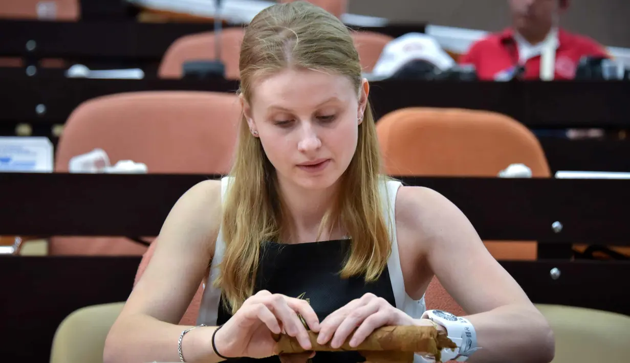 Peserta wanita menggulung cerutu selama kelas master dalam Festival Havana Cigar ke-20 di Istana Konvensi di Havana, Kuba (28/2). (AFP Photo/Adalberto Roque)