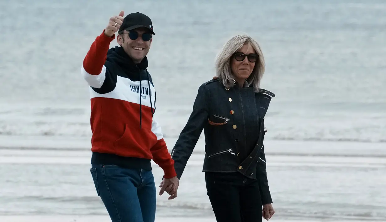 <p>Presiden Prancis Emmanuel Macron dan istrinya Brigitte Macron melambaikan tangan saat berjalan di sepanjang pantai di Le Touquet, menjelang putaran kedua pemilihan presiden Prancis, Sabtu (23/4/2022). Emmanuel Macron berada di posisi terdepan untuk memenangkan pemilihan kembali Minggu, 24 April 2022 dalam Pilpres Prancis. (AP Photo/Thibault Camus)</p>