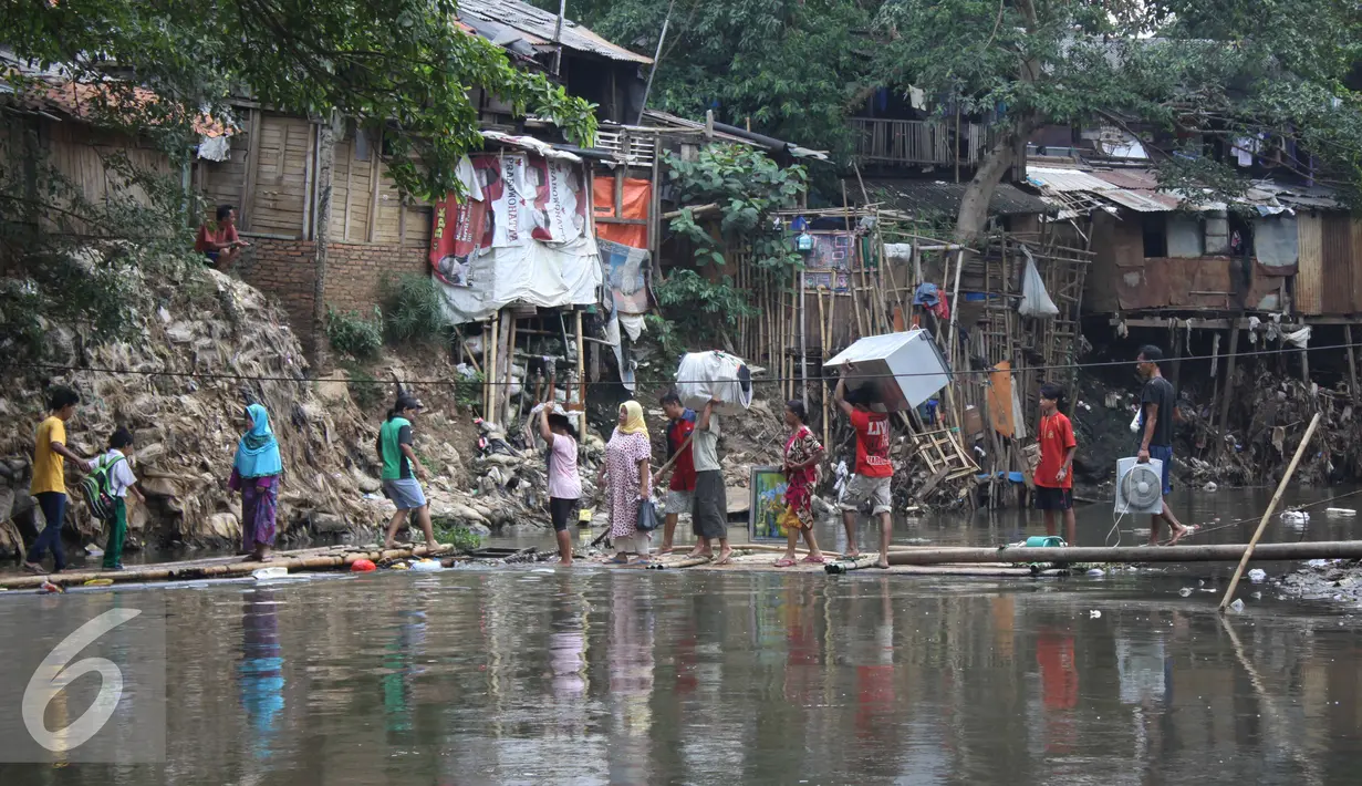 Sejumlah warga membawa barang miliknya menyeberangi kali Ciliwung usai penggusuran di Kampung pulo, Jakarta, Jumat (21/8/2015). Penggusuran terkait rencana Pemprov DKI Jakarta yang akan melakukan normalisasi Kali Ciliwung. (Liputan6.com/Gempur Surya)