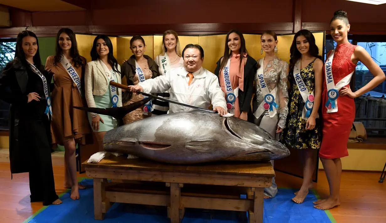 Sejumlah kontestan Miss Internasional berfoto bersama dengan Presiden Sushi-Zanmai, Kiyoshi Kimura (tengah) dan seekor tuna sirip biru seberat 250 Kg di Tokyo, Jepang (12/11). (AFP Photo/Toshifumi Kitamura)