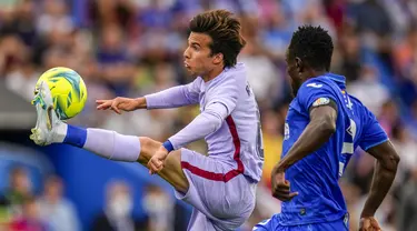 Pemain Barcelona Riqui Puig (kiri) berebut bola dengan pemain Getafe Djene Dakonam pada pertandingan sepak bola La Liga di Stadion Coliseum Alfonso Perez, Getafe, Spanyol, 15 Mei 2022. Pertandingan berakhir imbang 0-0. (AP Photo/Manu Fernandez)