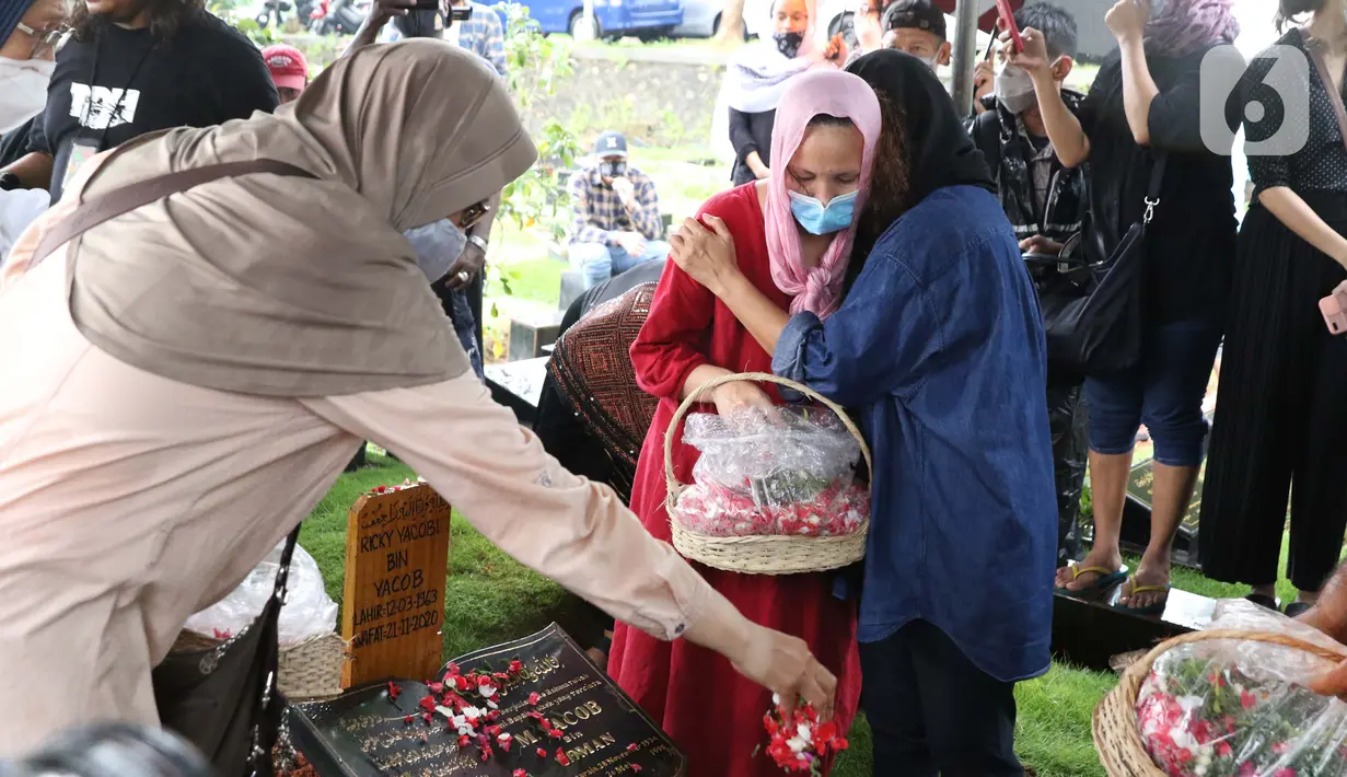 Istri mantan penggawa Timnas Indonesia Ricky Yacobi, Harly Ramayani (kanan) memeluk kerabat usai proses pemakaman suaminya di TPU Tanah Kusir, Jakarta, Sabtu (21/11/2020). Ricky Yacobi meninggal dunia pada Sabtu (21/11) akibat serangan jantung pada usia 57 tahun. (Liputan6.com/Helmi Fithriansyah)