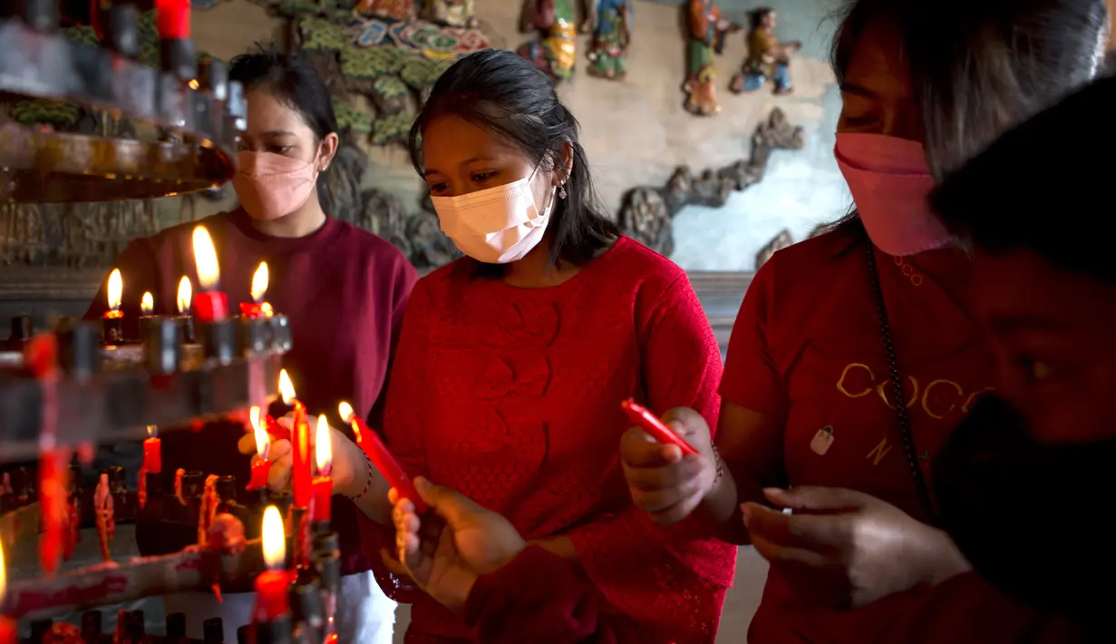 Warga etnis Tionghoa mengenakan masker berdoa untuk merayakan Tahun Baru Imlek di Bali, Selasa (1/2/2022). Orang-orang di seluruh Asia bersiap untuk perayaan Imlek yang diredam di tengah kekhawatiran atas virus corona dan varian omicron yang mulai merajalela. (AP Photo/Firdia Lisnawati)